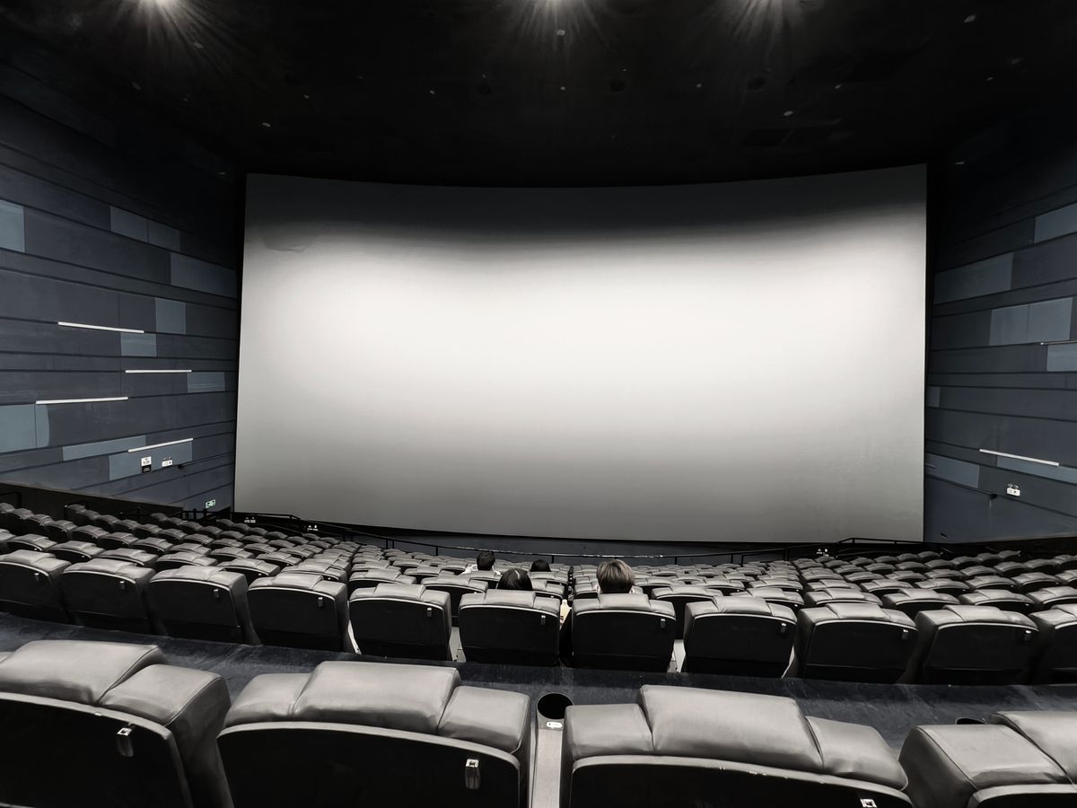 Movie theatre auditorium with a large lit screen and rows of empty seats