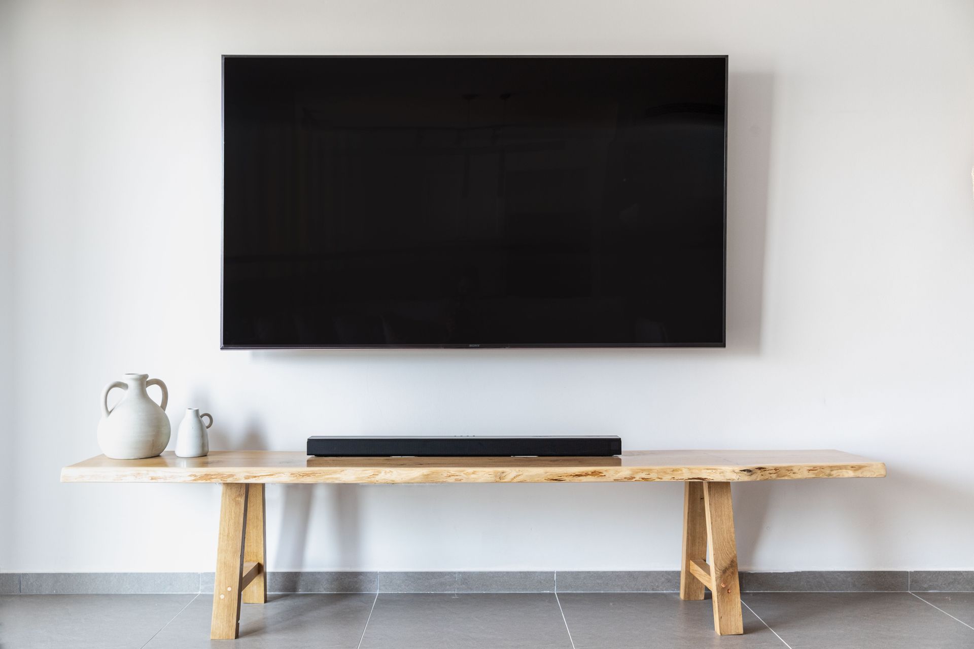 Flat-screen television mounted above a wooden console in a sunlit living room